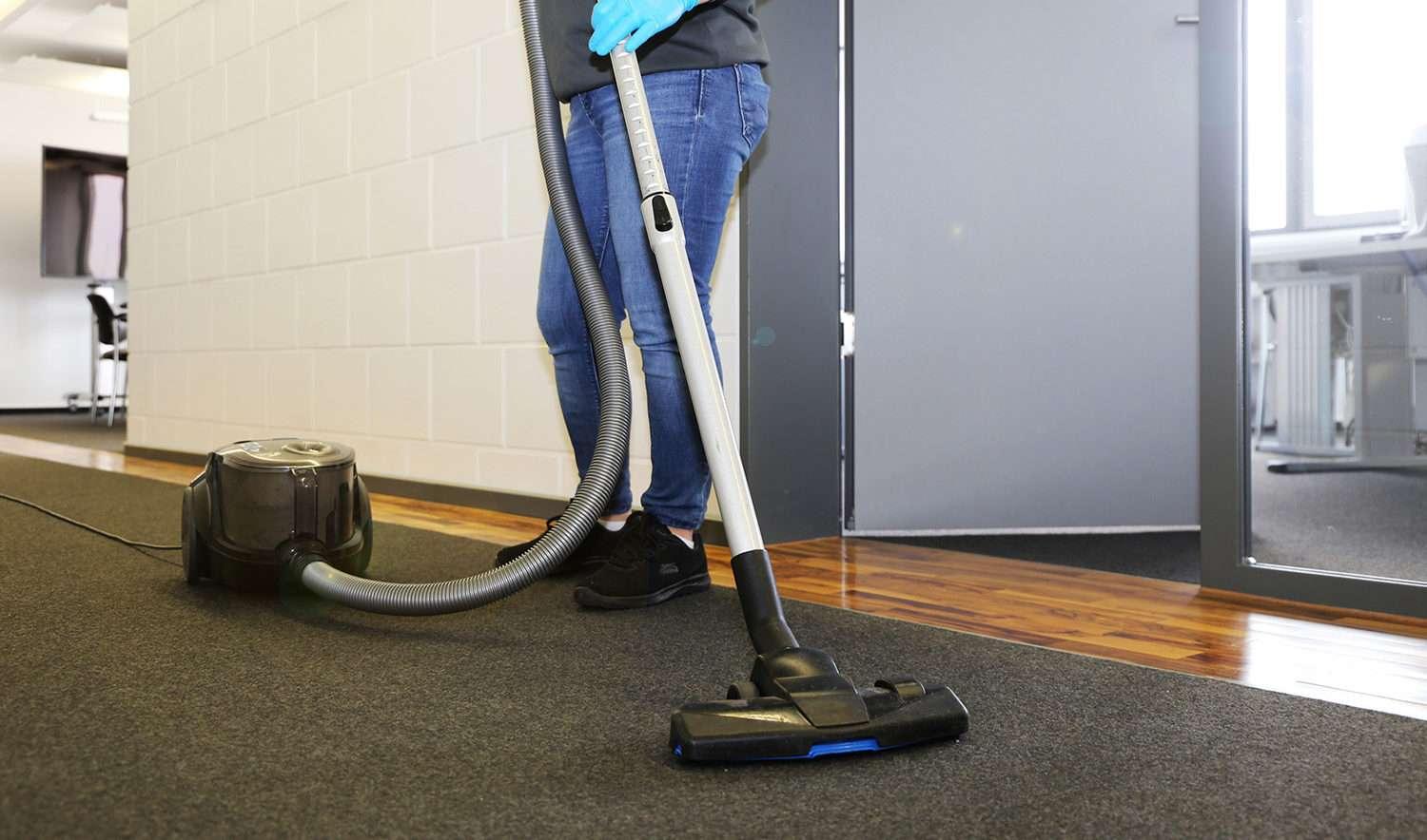 Office cleaning: Cleaner vacuums the corridor of an office
